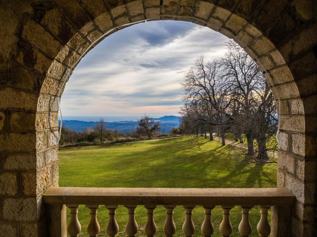 an arched window with a view of a green field at Gîte Marronnier in Tourrettes-sur-Loup