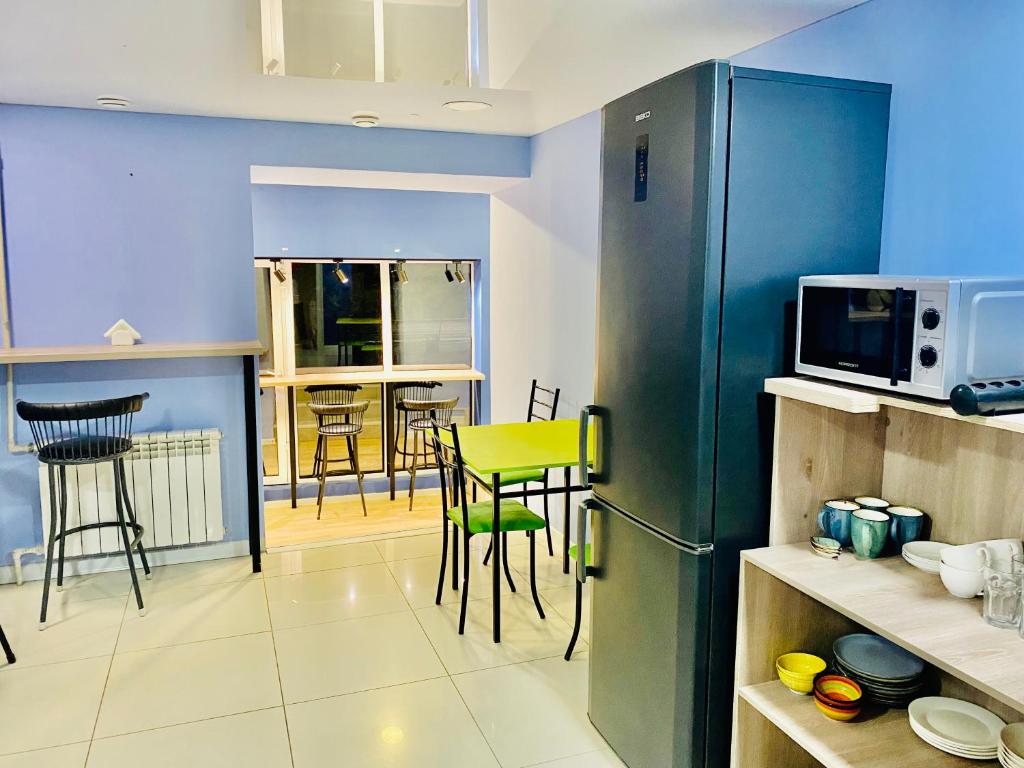 uma cozinha com um frigorífico verde e uma mesa e cadeiras em Like Home Hostel na Shevchenko em Almaty