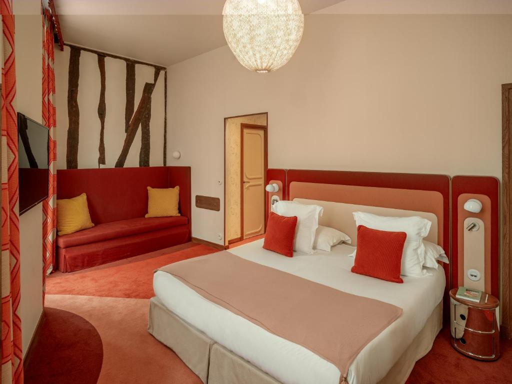 a bedroom with a large bed and a red couch at Hôtel Saint-André des Arts in Paris