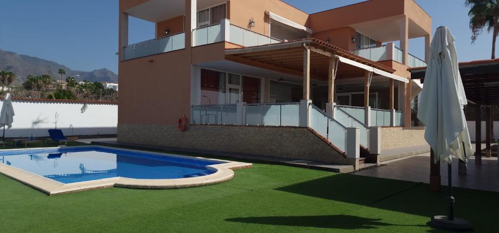 a house with a swimming pool in front of a building at Bright 4 bedroom Villa, Pool and Tennis court in Playa Paraiso