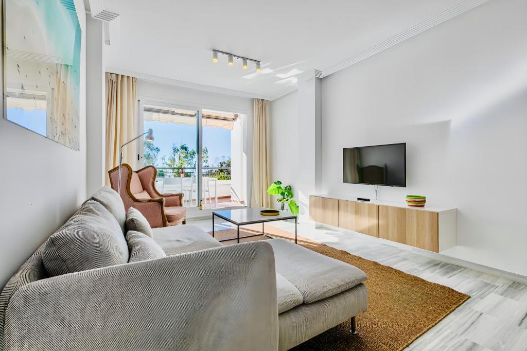 a living room with a couch and a tv at El Lago de Los Arqueros, Benahavís in Benahavís