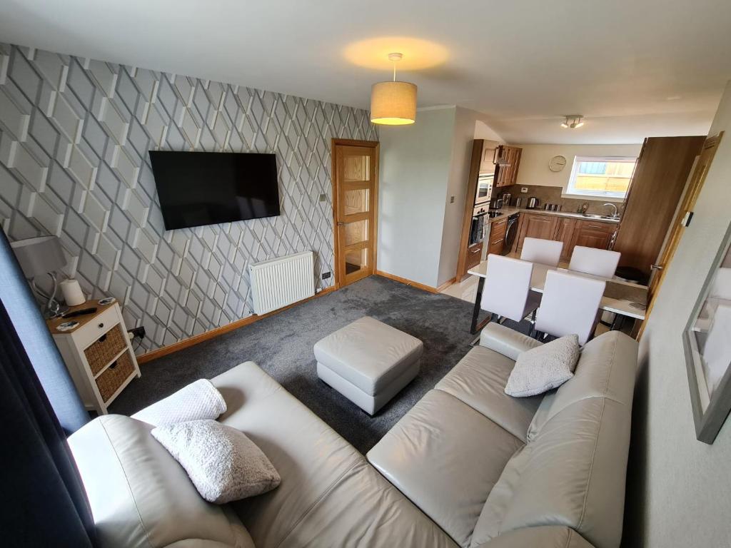 a living room with a couch and a tv at Bruxie Holiday Cottages - River Cottage in Maud