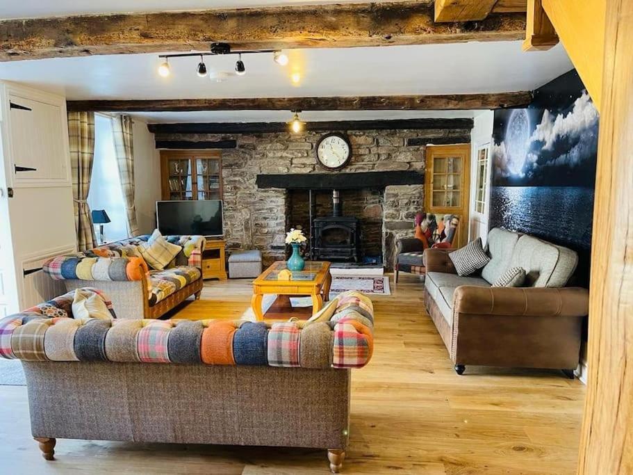 a living room with couches and a stone fireplace at Onnen Fawr Farmhouse in Brecon