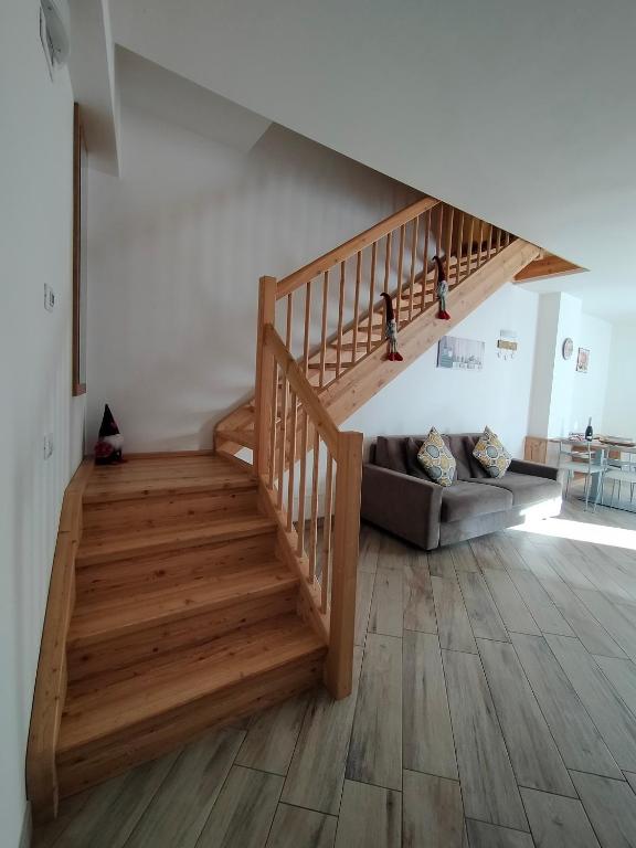 a wooden staircase in a living room with a couch at Appartamento Morettina con terrazzo in Levico Terme