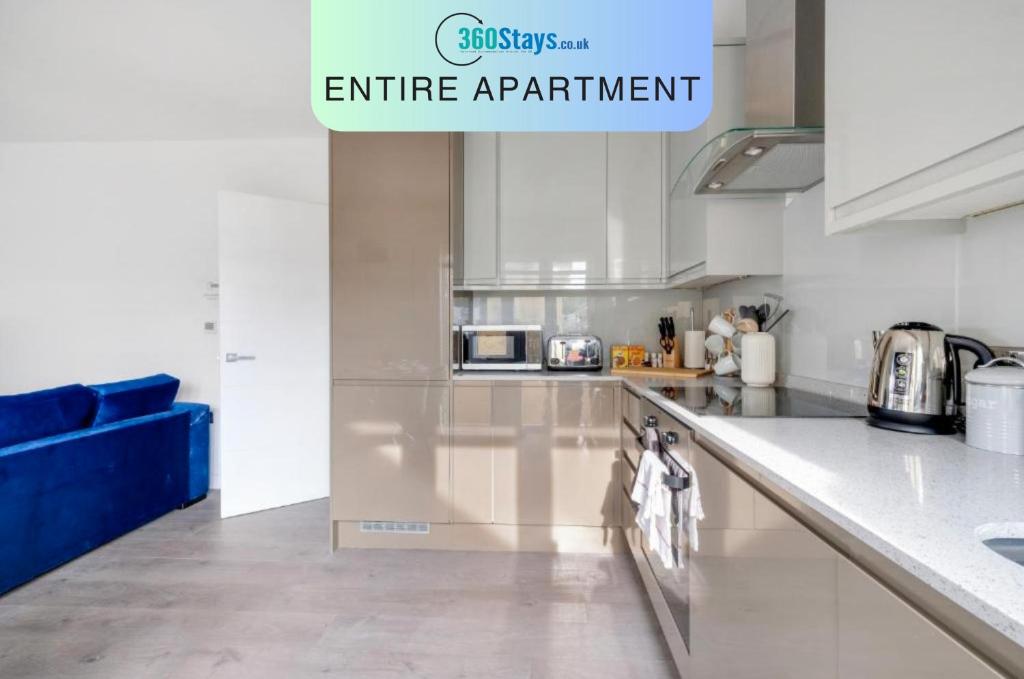 a kitchen with stainless steel appliances and a blue couch at Town Center 2 bed Serviced Apartment 08 with parking, Surbiton By 360Stays in Surbiton