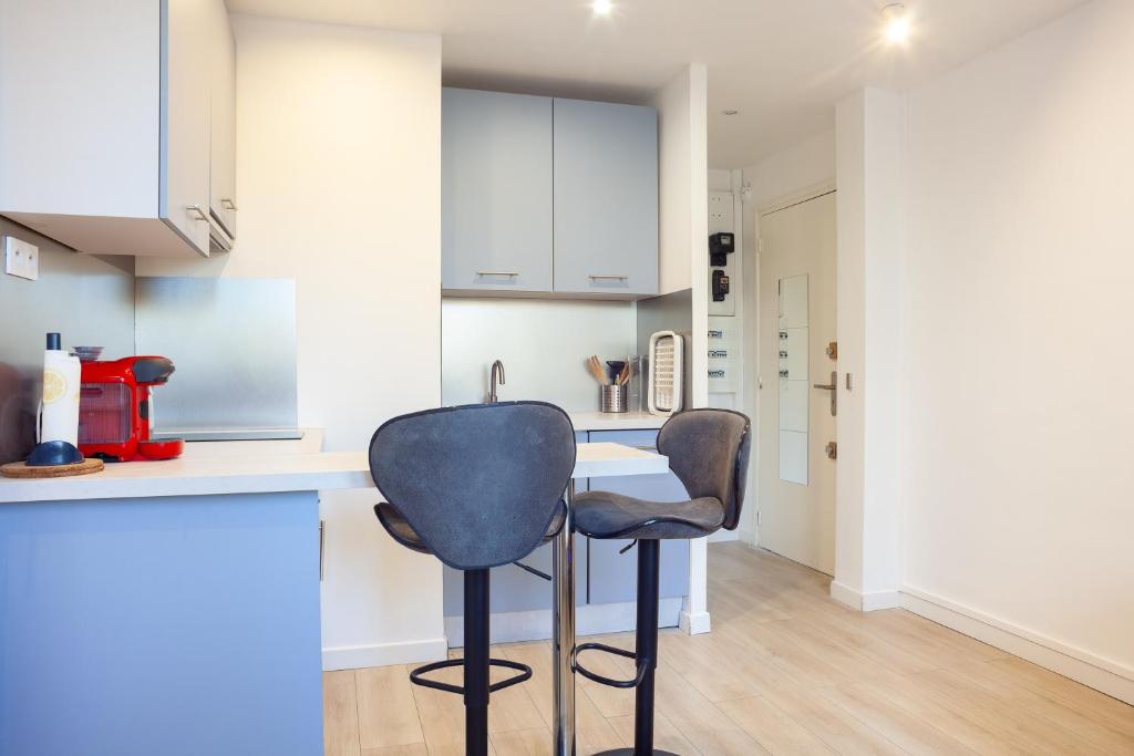 una cocina con 2 taburetes en una cocina con armarios blancos en Appartement Cassis, en Cassis