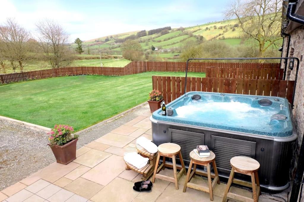 a hot tub sitting on a patio with two stools at Sycamore Tree Barn in Brecon