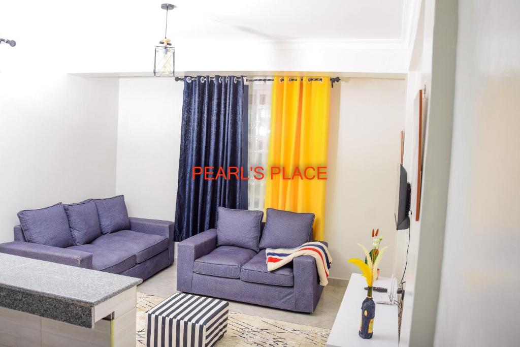 a living room with two purple couches and a yellow curtain at Pearl's Place in Meru