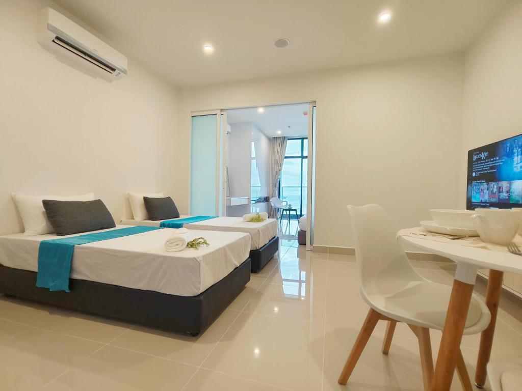 1 dormitorio con 2 camas, mesa y TV en Just Chillin Seaview, en Kota Kinabalu