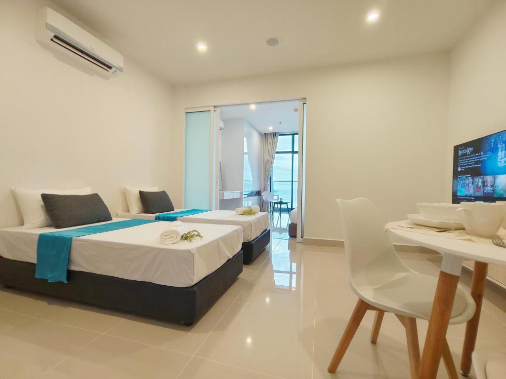 a bedroom with two beds and a table and a tv at Lasa Lasa Sojourn 4 pax at The Shore seaview suites in Kota Kinabalu