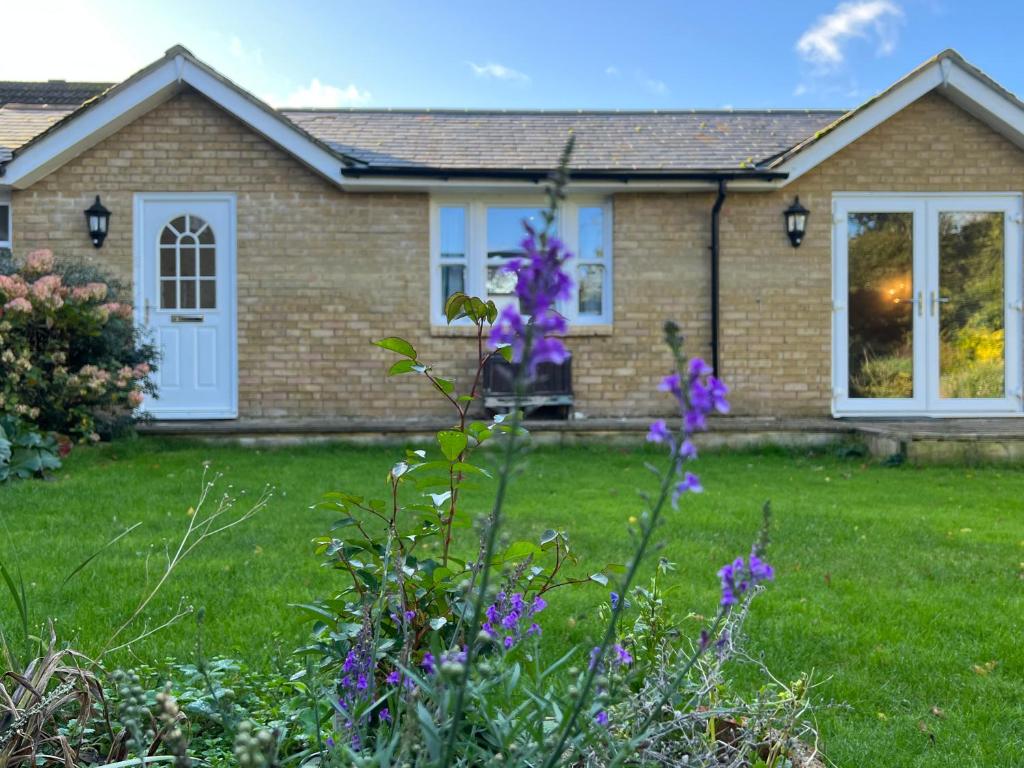 a house with purple flowers in the yard at Cosy Hillside Annex in Stanwick