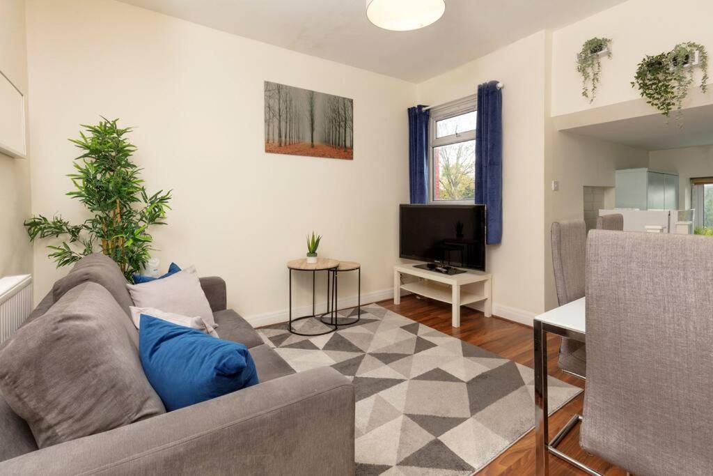 Charming North London Apartment في لندن: غرفة معيشة مع أريكة وتلفزيون