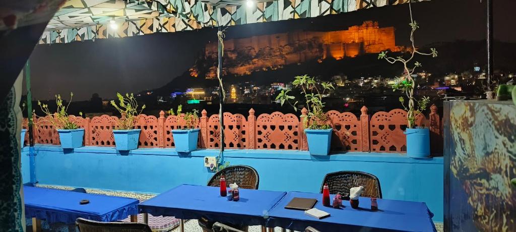 a restaurant with blue tables and potted plants on a wall at Musa's Homestay in Jodhpur