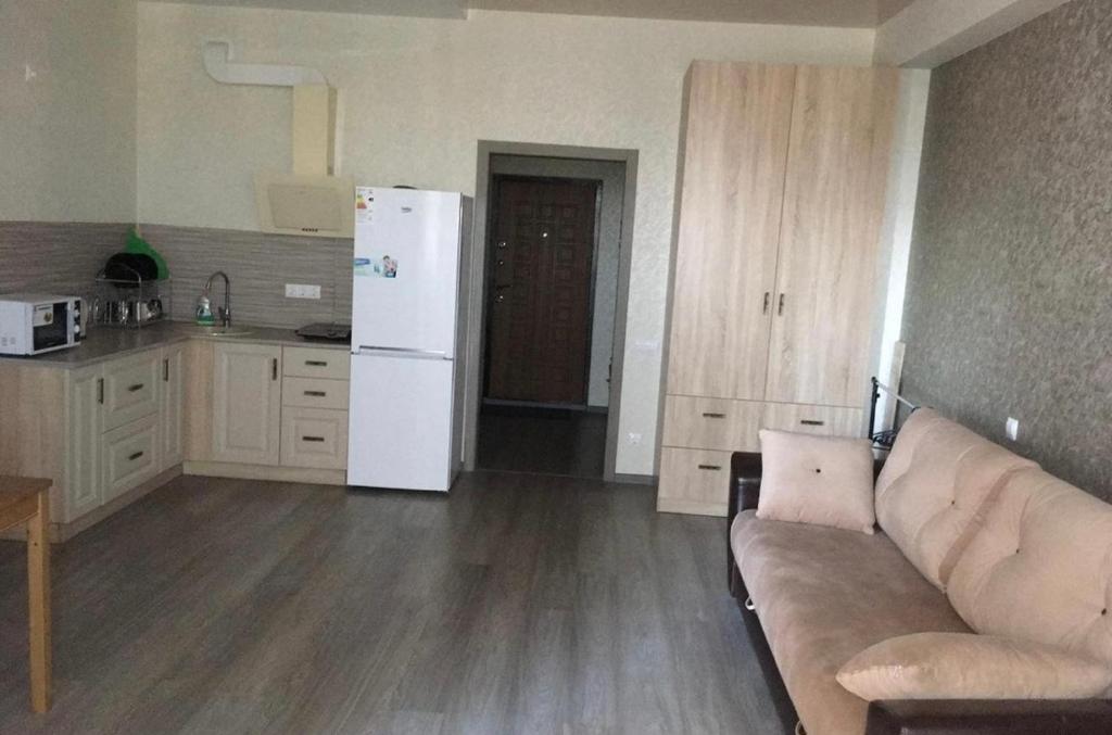 uma sala de estar com um sofá e um frigorífico branco em VIP apart 413 em Tbilisi