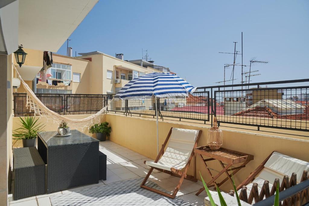 patio con sombrilla y sillas en el balcón en Calm & Relaxing Apartment w/ Terrace in Almada en Almada