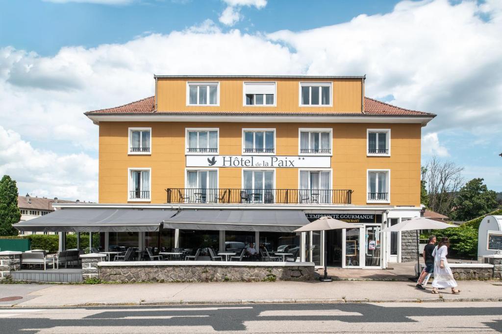 un hotel amarillo con gente caminando delante de él en Hôtel De La Paix, en Gérardmer