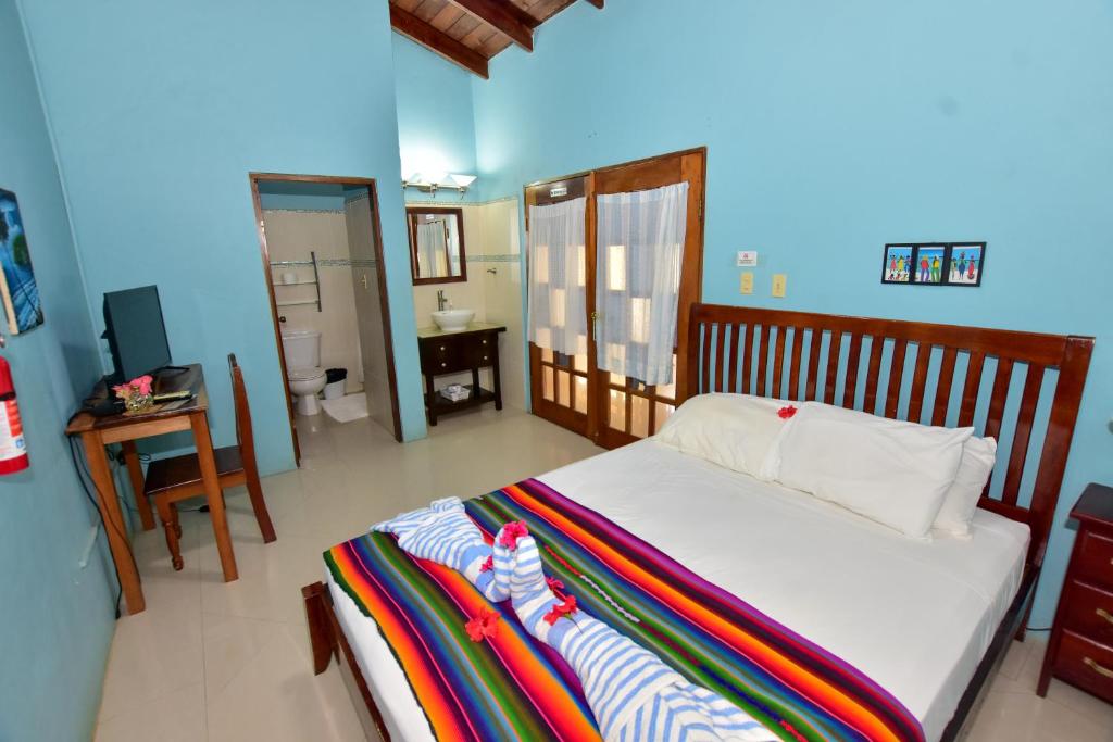 a bedroom with a bed and a bathroom with a television at Caribbean Shores Belize in Hopkins