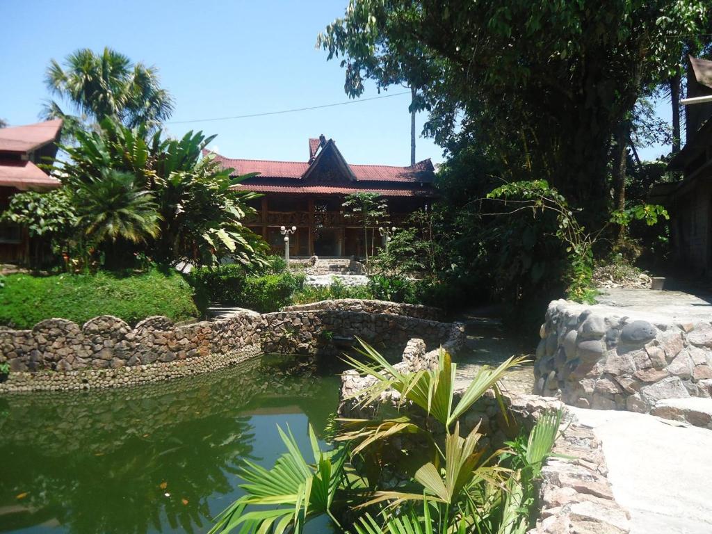 a garden with a pond in front of a building at Hosteria Hachacaspi in Puyo