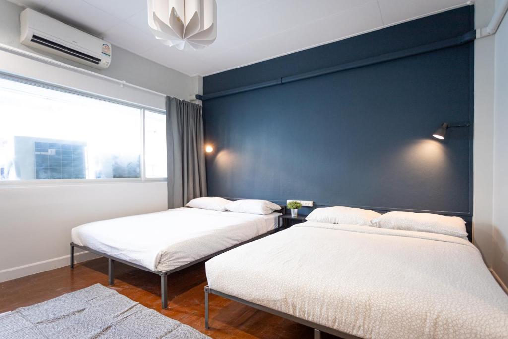 A4 Cosy Twin large beds - Silom في بانكوك: سريرين في غرفة ذات جدار أزرق