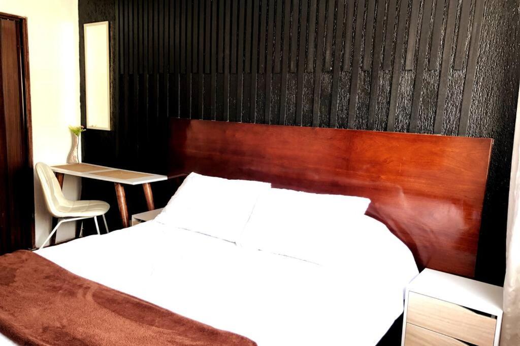een slaapkamer met een bed en een houten hoofdeinde bij Apto confortable zona estratégica al Aeropuerto in Bogota