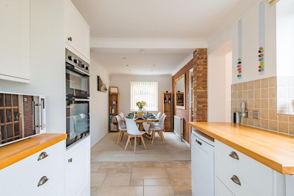 a kitchen with white cabinets and a dining room at Shalom - holiday home with panoramic views of the sea in Kingsdown