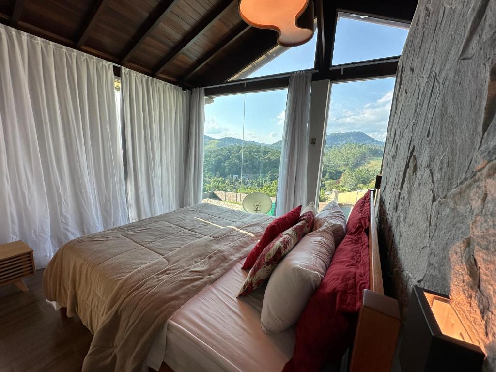 een slaapkamer met een bed en een groot raam bij Chalé Requinte da Serra in Miguel Pereira