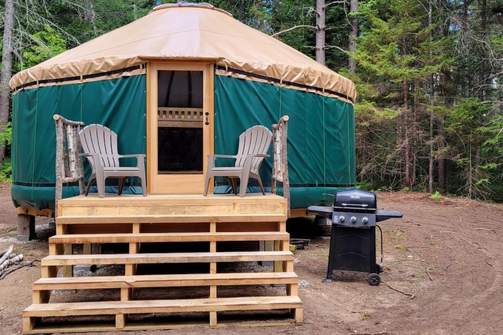 a yurt with two chairs and a grill at Allie Mae Yurt nestled in the woods in Brownfield