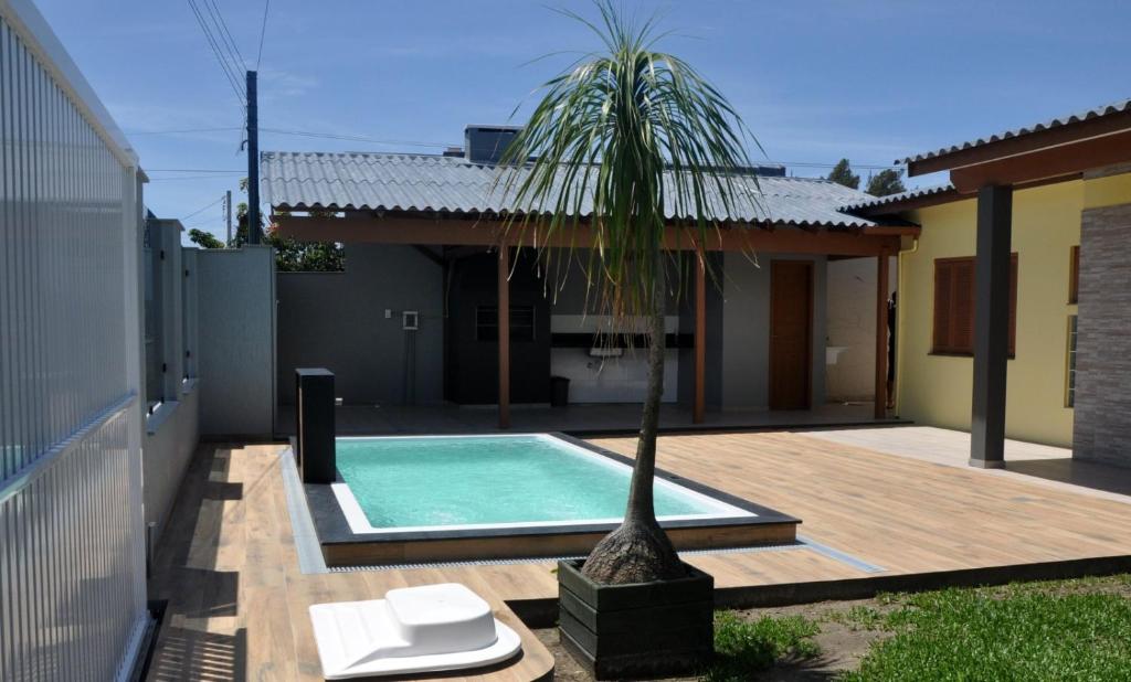 a palm tree sitting next to a swimming pool at Casa Com Quatro Dormitórios Pertinho Do Mar Em Capão Da Canoa in Capão da Canoa