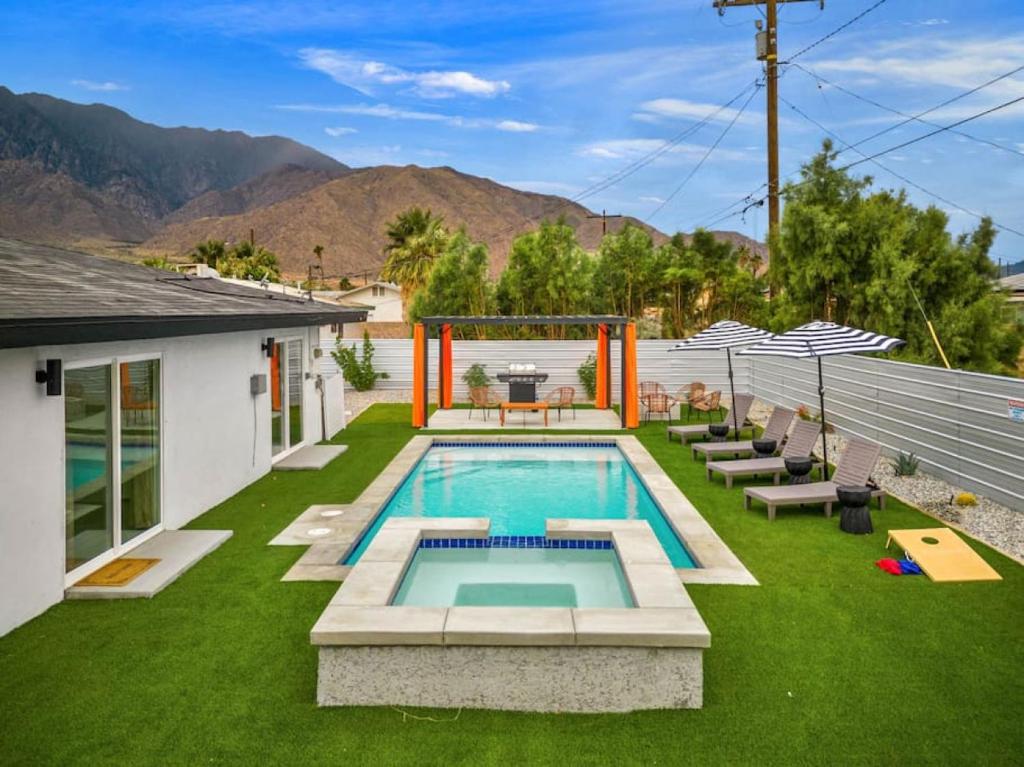 a backyard with a swimming pool and green grass at NEW Sip Sip Away A Vibrant Pool and Hot Tub Retreat in Palm Springs