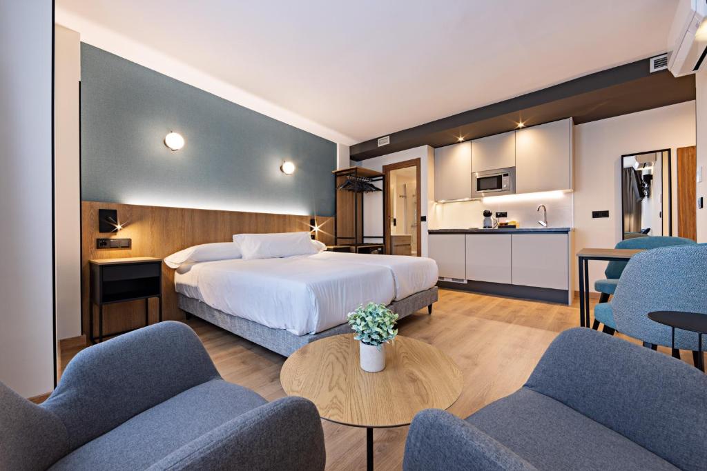 ein Hotelzimmer mit einem Bett und blauen Stühlen in der Unterkunft Apartahotel Colón 27 in Palencia