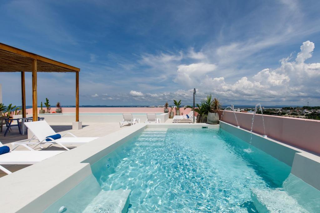 uma piscina com cadeiras e o oceano ao fundo em Bondo Estudio em Cartagena de Indias