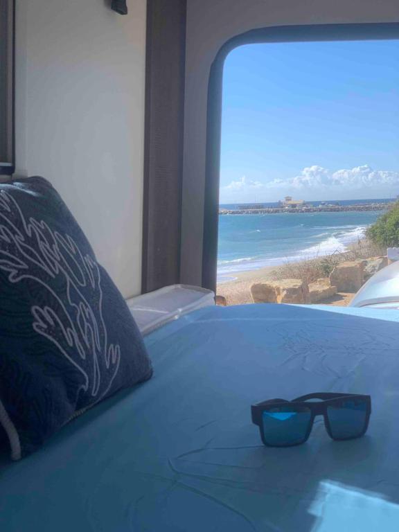 un par de gafas de sol sentadas en una cama con una playa en Andalusian Lifestyle, en Marbella