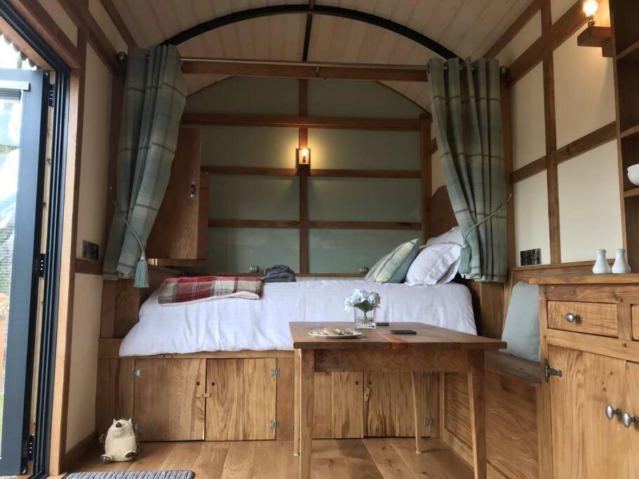 a bedroom with a large bed and a table at The Orient Express Shepherd's Hut with Hot Tub in Brecon