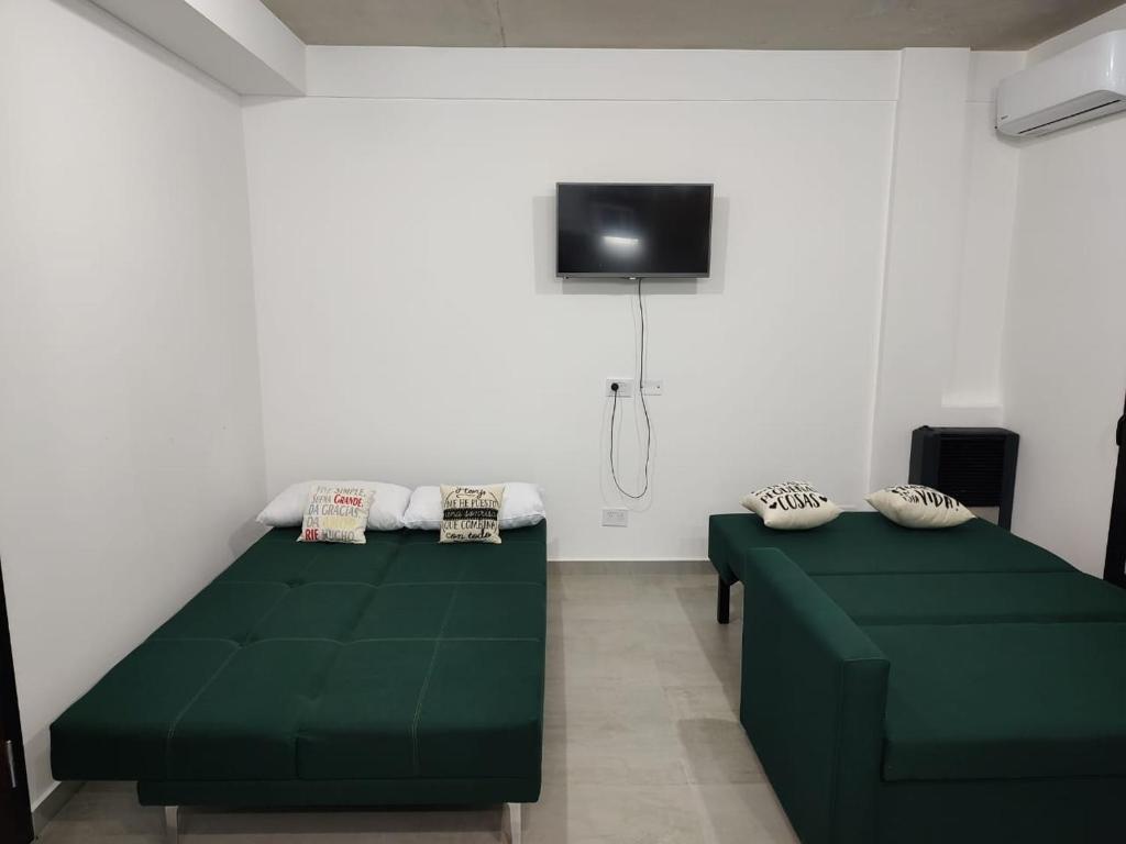 a living room with two green beds and a tv at La Plaza in Sunchales