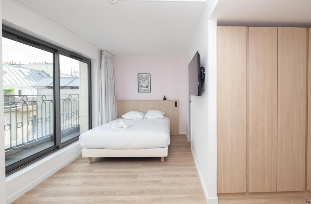 a bedroom with a bed and a large window at FINESTATE Coliving Champs-Elysées in Paris