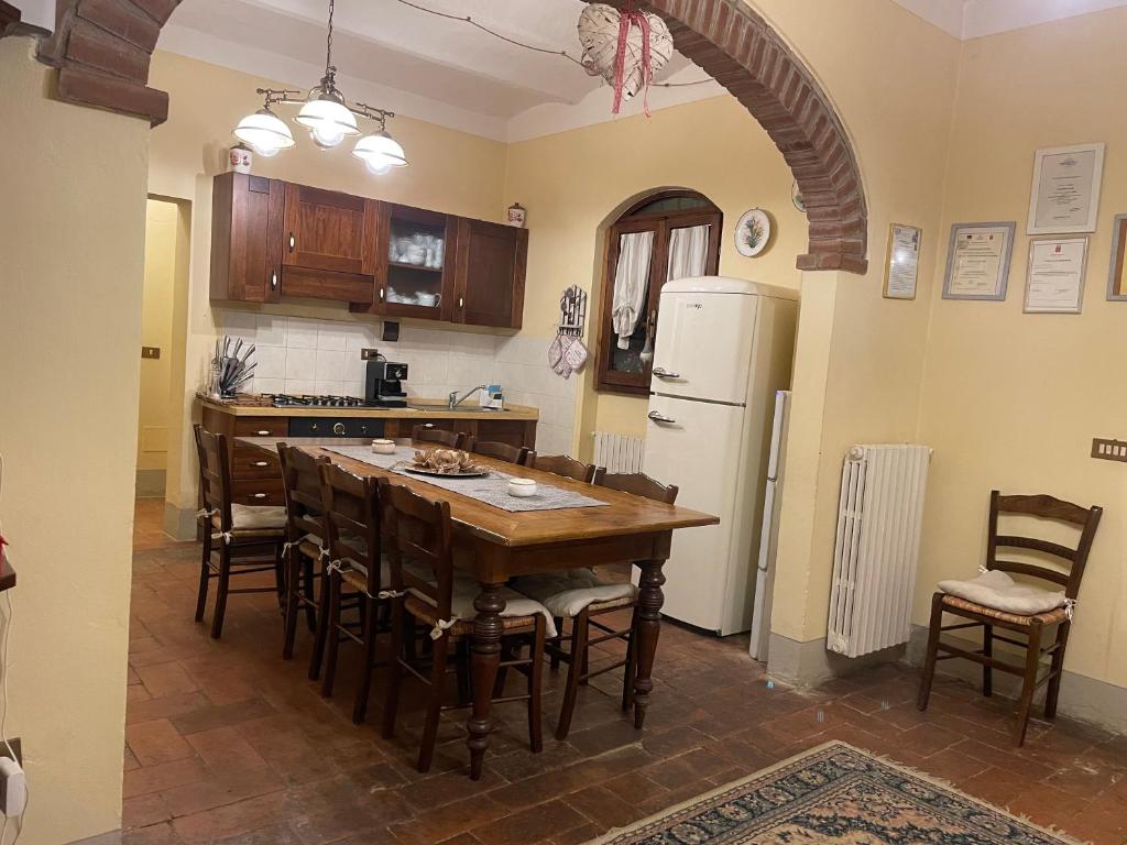 une cuisine avec une table, des chaises et un réfrigérateur dans l'établissement Agriturismo Podere Delle Querci, à Castiglion Fiorentino