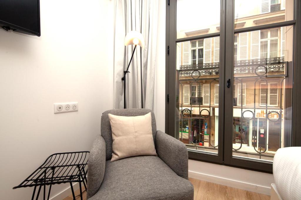 a living room with a chair and a window at FINESTATE Coliving Champs-Elysées in Paris