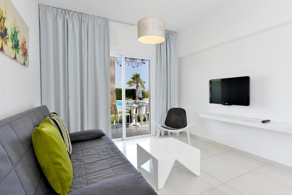a living room with a couch and a tv and a table at Mon Repos Hotel in Ayia Napa
