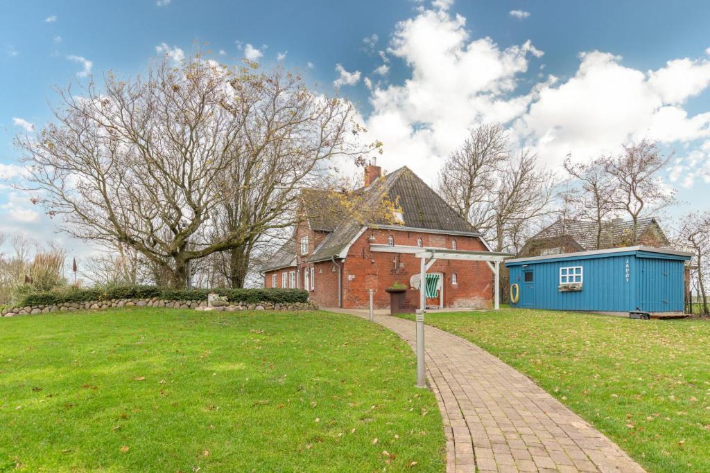 een stenen huis met een blauwe schuur in een tuin bij Juwel am Deich in Emmelsbüll-Horsbüll