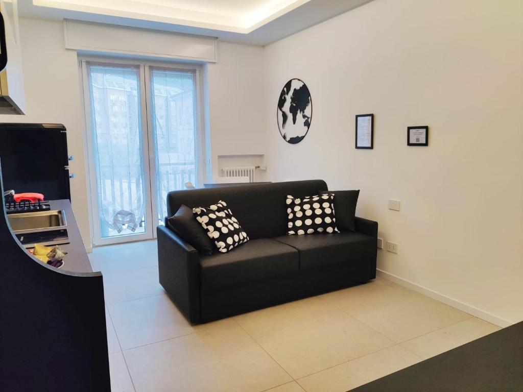 sala de estar con sofá negro y TV en Alimagia, en Lecco