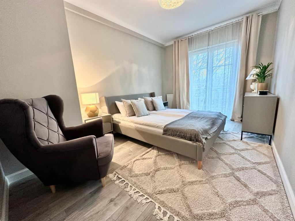 a bedroom with a bed and a chair and a window at Apartament nad Łyną by RENT4YOU in Olsztyn