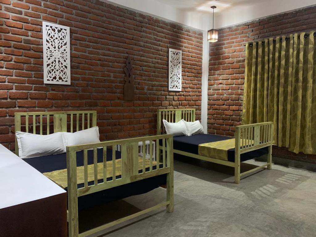 a room with two cribs and a brick wall at Sky 14 Resort Yala in Madam