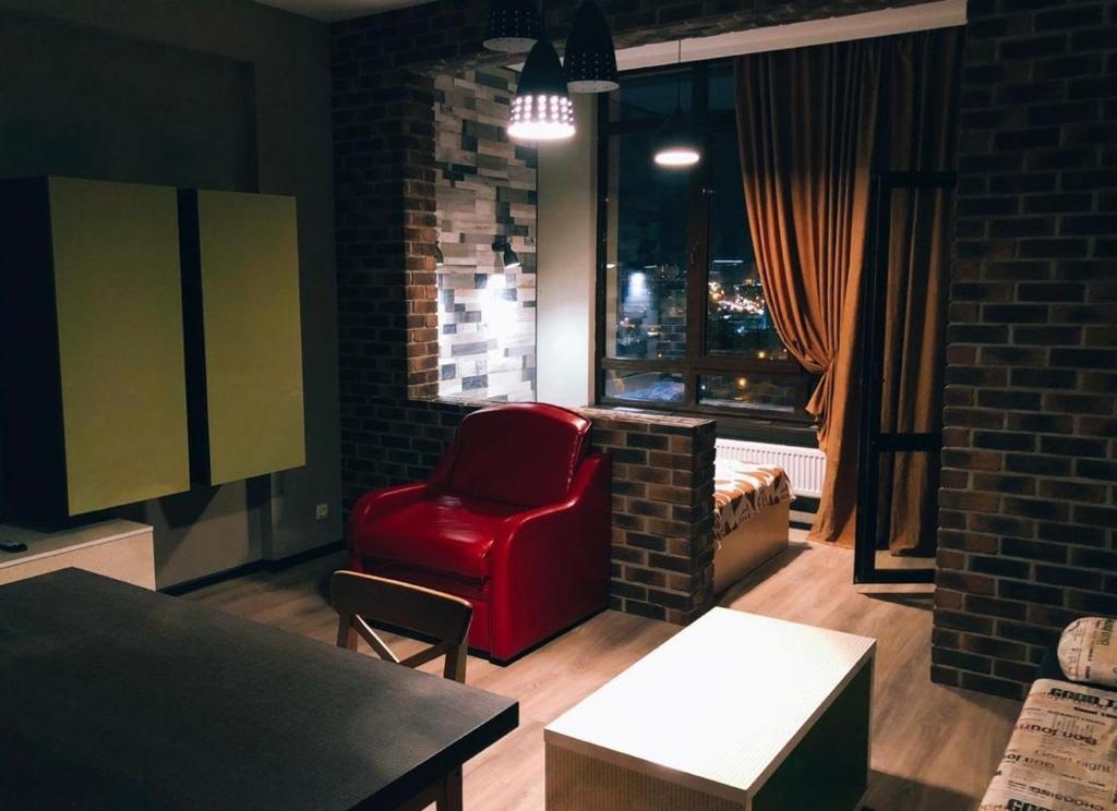 een woonkamer met een rode stoel en een raam bij VIP apart 419 in Tbilisi City