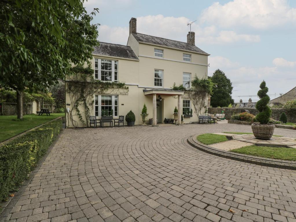 a cobblestone driveway in front of a white house at The Gate House in Cirencester