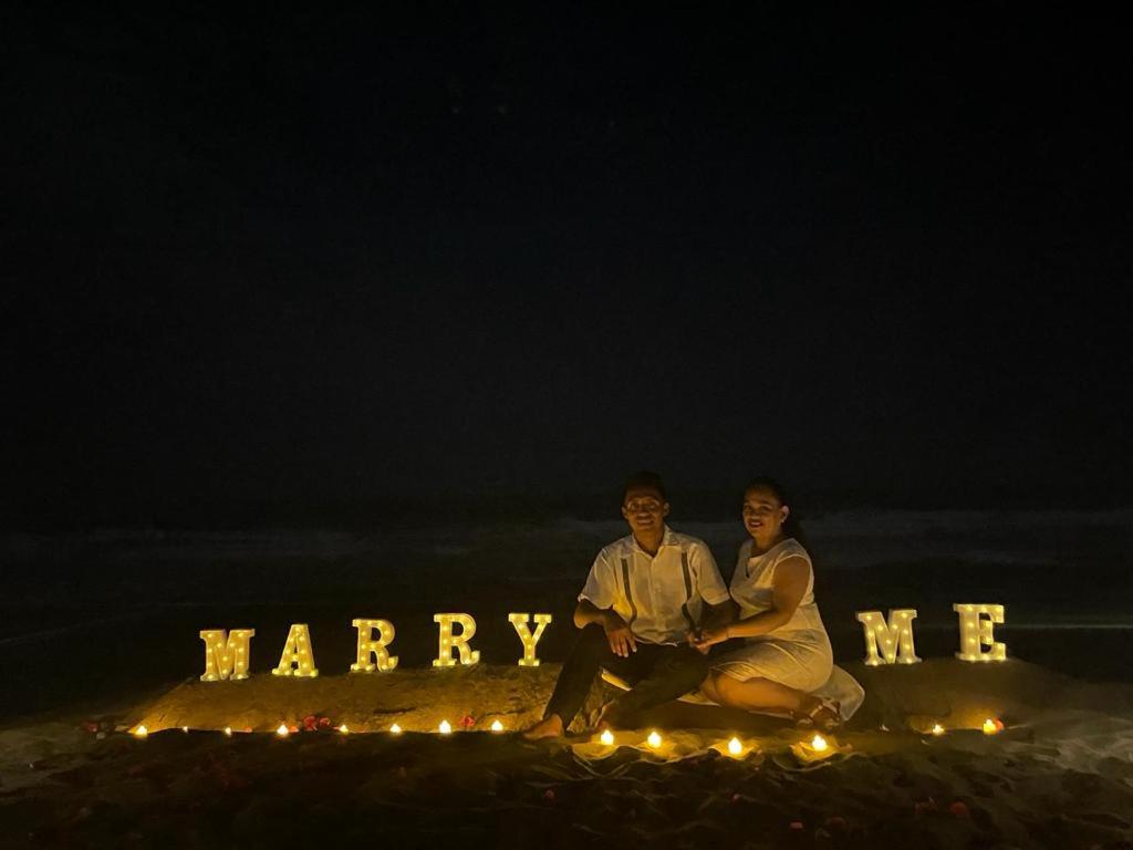 un hombre y una mujer sentados frente a una señal de matrimonio en Palapa Abraham, 