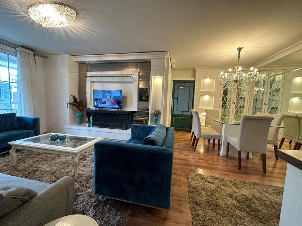 a living room with a blue couch and a table at Amplo apartamento 03 dorm Centro de Gramado in Gramado