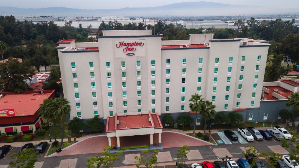 - un grand bâtiment blanc avec un panneau dans l'établissement Hampton Inn by Hilton Guadalajara-Aeropuerto, à Guadalajara