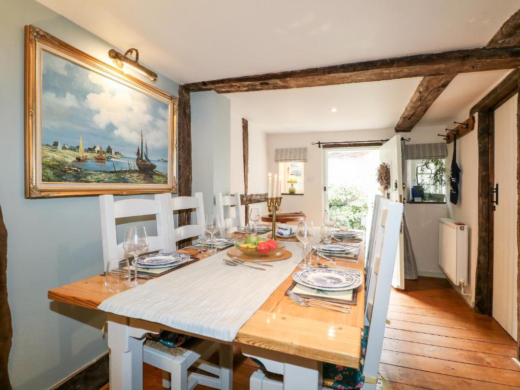 a dining room with a table and a painting on the wall at Peppermint Cottage in Petworth