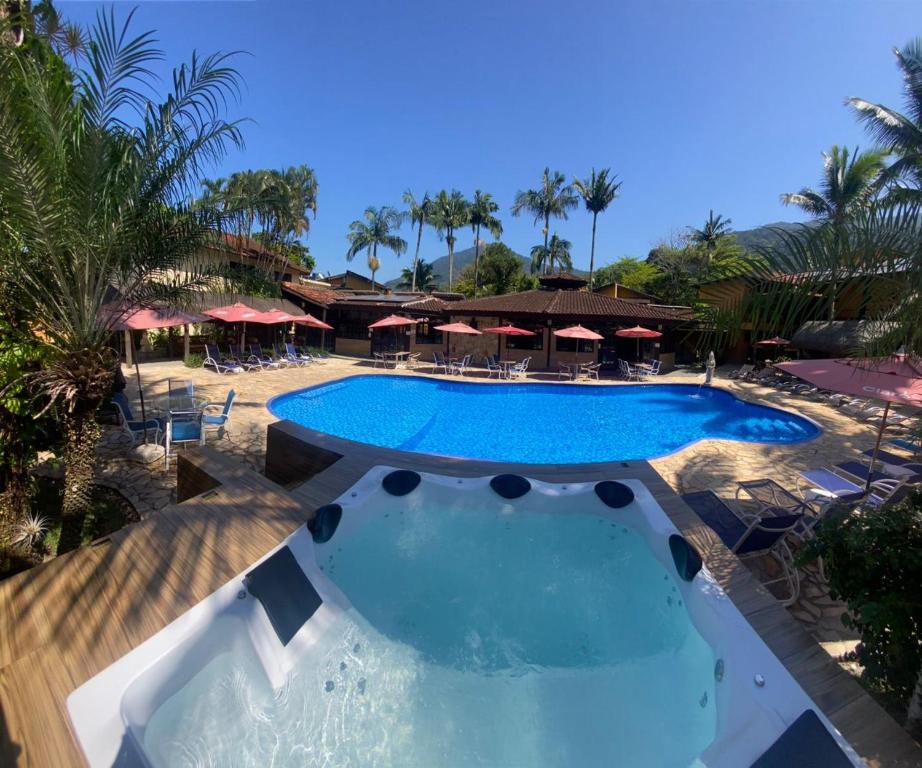 - une piscine dans un complexe avec des chaises et des parasols dans l'établissement Hotel Pousada dos Condes, à Maresias
