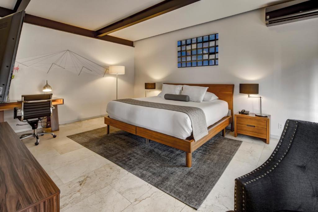 a bedroom with a bed and a desk and a television at MX Grand Suites in Mexico City
